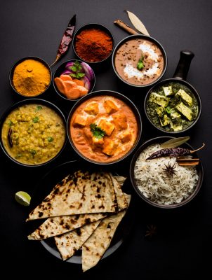 Indian Lunch or Dinner main course food in group includes Paneer Butter Masala, Dal Makhani, Palak Paneer, Roti, Rice etc, Selective focus